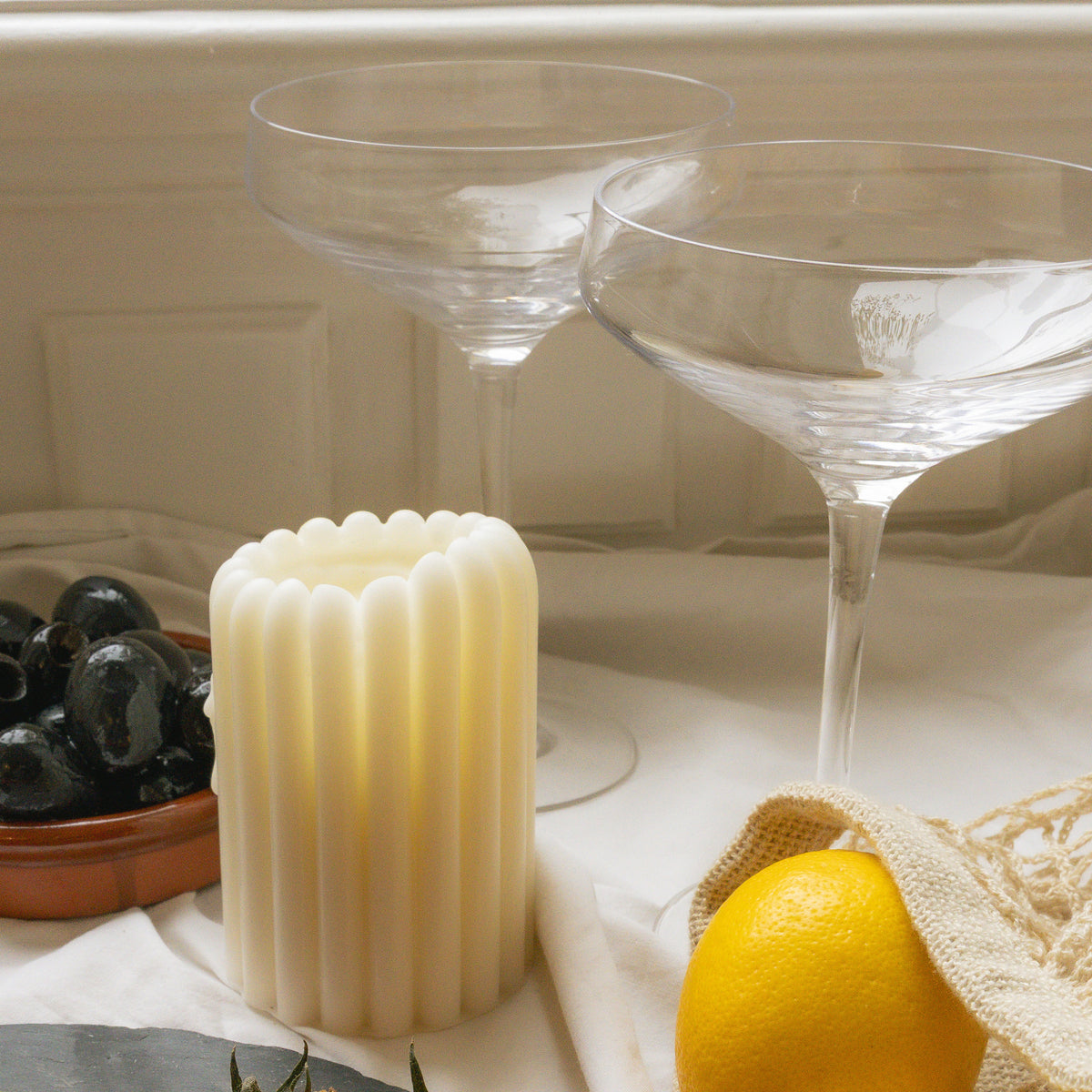Pillar Candle II on a summer table with olives, lemon and coupe glasses